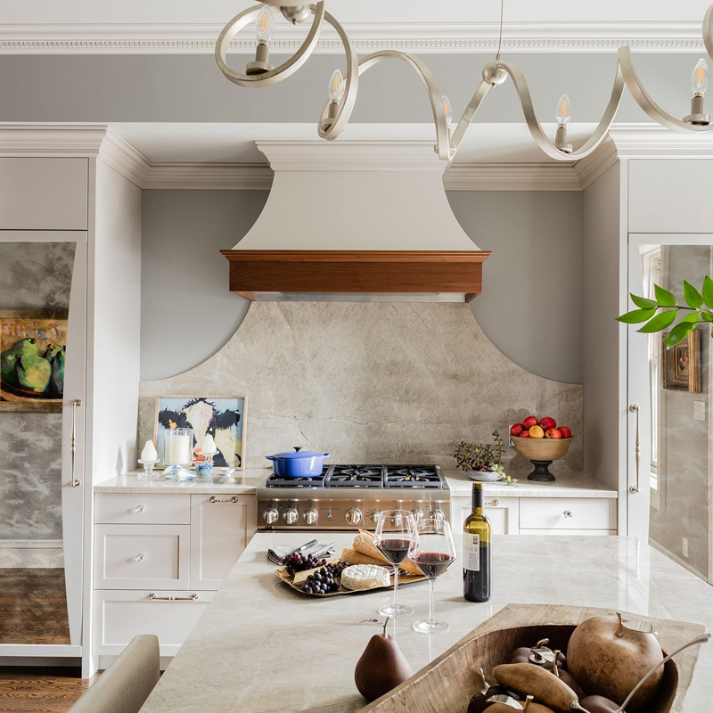 Soft lines in the ribbon chandelier and curved inlaid mirrors create movement in a traditionally hardlined kitchen.